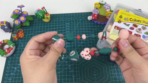 Strand of finished clay beads being lined up on thread before closing the bracelet