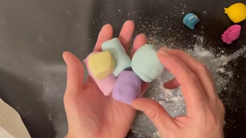 how to Condition Polymer Clay By Hand IdeaBare hands holding and squeezing together several conditioned pastel polymer clay blocks in mint, yellow, lavender, and blue to show their softened and workable texture. s 5