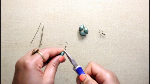 Four mica-coated beads threaded on a wooden skewer suspended across a foil-lined baking tray.