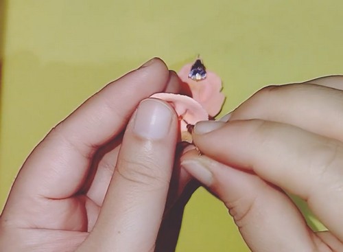 A ruffled peach clay earring disc with a crystal stud post pressed into the centre.
