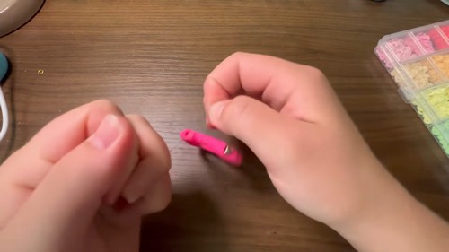 Trimming the cord end after finishing a strand of pink clay beads