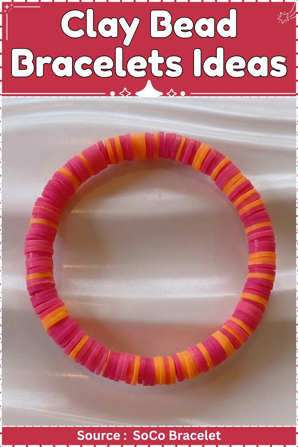 Finished clay bead bracelet made from alternating hot pink and orange heishi disc beads laid flat in a circle on a white rippled surface