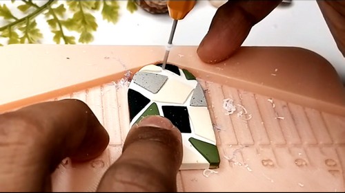 Pin vise drilling a hanging hole in a cured geometric clay earring.